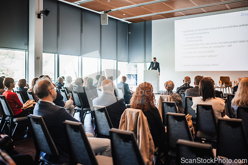 Image of Speaker giving a talk in conference hall at business event. Rear view of unrecognizable people in audience at the conference hall. Business and entrepreneurship concept.