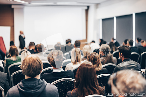 Image of Speaker giving a talk in conference hall at business event. Rear view of unrecognizable people in audience at the conference hall. Business and entrepreneurship concept.