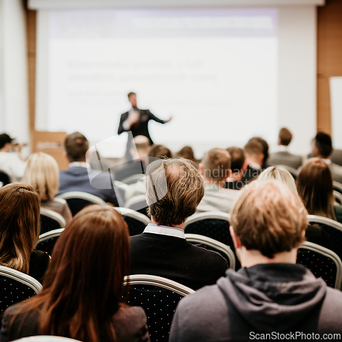 Image of Speaker giving a talk in conference hall at business event. Rear view of unrecognizable people in audience at the conference hall. Business and entrepreneurship concept.