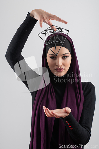 Image of Elegant Muslim woman in a hijab with a geometric structure in a conceptual portrait.