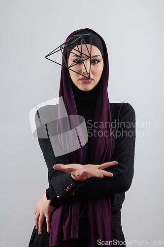 Image of Elegant Muslim woman in a hijab with a geometric structure in a conceptual portrait.