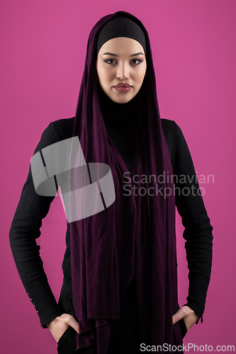 Image of Beautiful Muslim woman in a hijab posing elegantly in a studio with a pink background.
