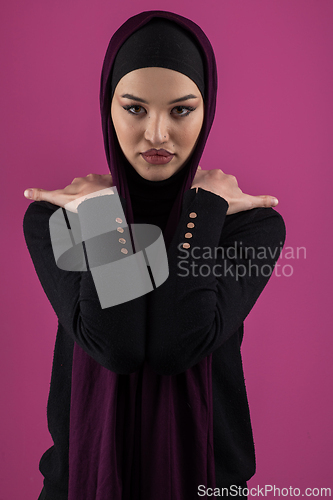 Image of Beautiful Muslim woman in a hijab posing elegantly in a studio with a pink background.