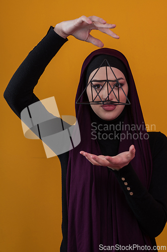 Image of Elegant Muslim woman in a hijab with a geometric structure in a conceptual portrait.