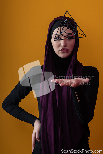 Image of Elegant Muslim woman in a hijab with a geometric structure in a conceptual portrait.