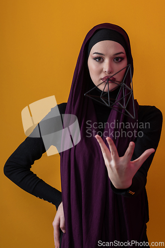 Image of Elegant Muslim woman in a hijab with a geometric structure in a conceptual portrait.