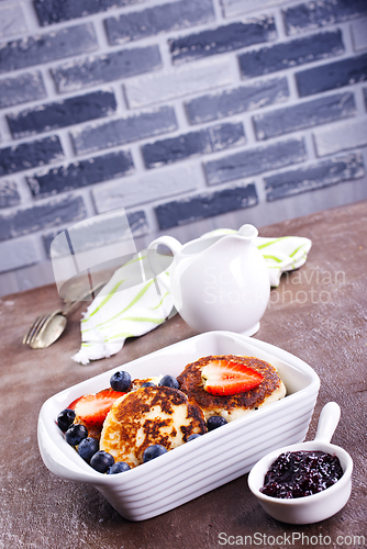 Image of Cottage cheese pancakes or syrniki with sour cream, honey and berries.