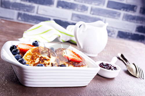 Image of Cottage cheese pancakes or syrniki with sour cream, honey and berries.