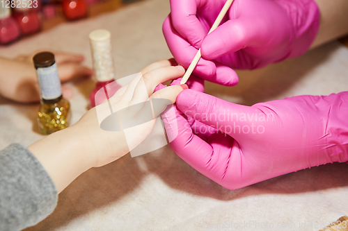 Image of Little girl is getting manicure in beauty salon, close-up.
