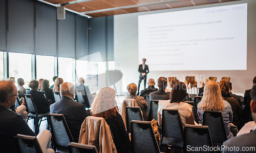 Image of Speaker giving a talk in conference hall at business event. Rear view of unrecognizable people in audience at the conference hall. Business and entrepreneurship concept.