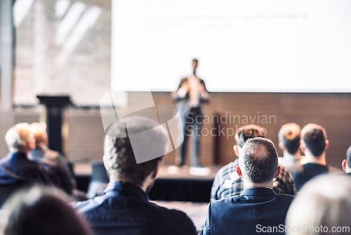 Image of Speaker giving a talk in conference hall at business event. Rear view of unrecognizable people in audience at the conference hall. Business and entrepreneurship concept.
