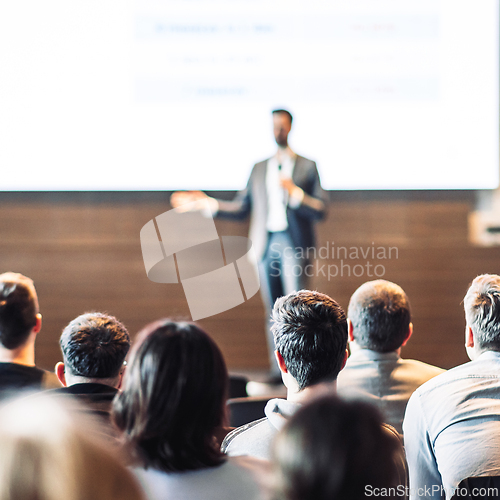 Image of Speaker giving a talk in conference hall at business event. Rear view of unrecognizable people in audience at the conference hall. Business and entrepreneurship concept.