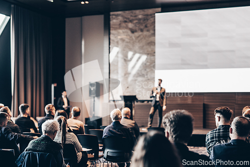 Image of Speaker giving a talk in conference hall at business event. Rear view of unrecognizable people in audience at the conference hall. Business and entrepreneurship concept.