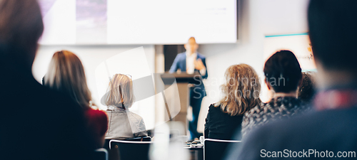 Image of Speaker giving a talk in conference hall at business event. Rear view of unrecognizable people in audience at the conference hall. Business and entrepreneurship concept.