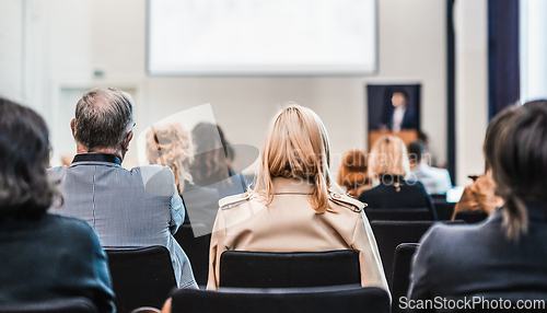 Image of Speaker giving a talk in conference hall at business event. Rear view of unrecognizable people in audience at the conference hall. Business and entrepreneurship concept.