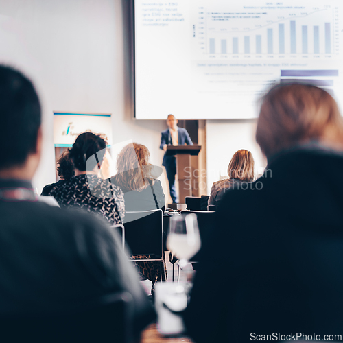 Image of Speaker giving a talk in conference hall at business event. Rear view of unrecognizable people in audience at the conference hall. Business and entrepreneurship concept.
