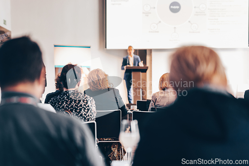 Image of Speaker giving a talk in conference hall at business event. Rear view of unrecognizable people in audience at the conference hall. Business and entrepreneurship concept.