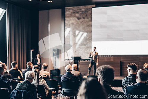 Image of Speaker giving a talk in conference hall at business event. Rear view of unrecognizable people in audience at the conference hall. Business and entrepreneurship concept.