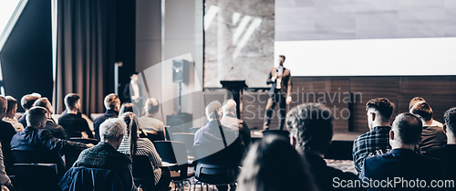 Image of Speaker giving a talk in conference hall at business event. Rear view of unrecognizable people in audience at the conference hall. Business and entrepreneurship concept.