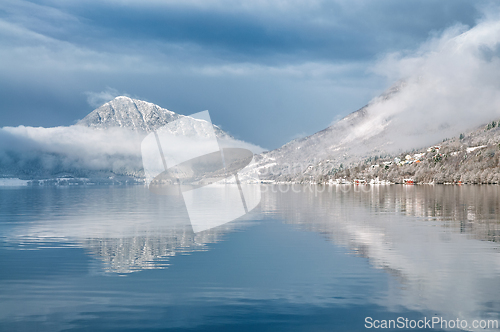 Image of Reflection of mountains and clouds on a tranquil lake in winter 