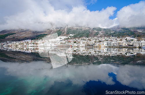 Image of Snow-covered village by a lake reflects stunning mountain scener