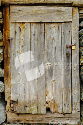Image of Rustic wooden door attached to stone wall in a countryside setti