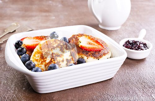 Image of Cottage cheese pancakes or syrniki with sour cream, honey and berries.