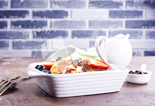 Image of Cottage cheese pancakes or syrniki with sour cream, honey and berries.
