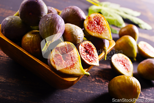Image of A close-up photo of fresh figs, some whole and some halved, displayed in a wooden bowl