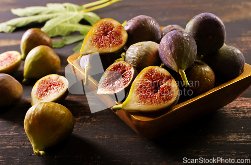 Image of A close-up photo of fresh figs, some whole and some halved, displayed in a wooden bowl