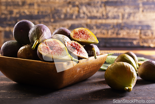 Image of A close-up photo of fresh figs, some whole and some halved, displayed in a wooden bowl