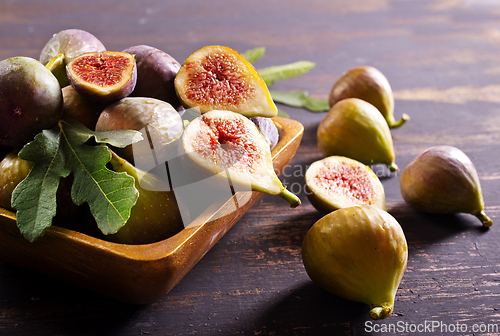 Image of A close-up photo of fresh figs, some whole and some halved, displayed in a wooden bowl