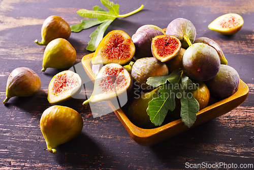 Image of A close-up photo of fresh figs, some whole and some halved, displayed in a wooden bowl