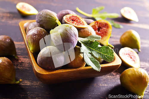 Image of A close-up photo of fresh figs, some whole and some halved, displayed in a wooden bowl