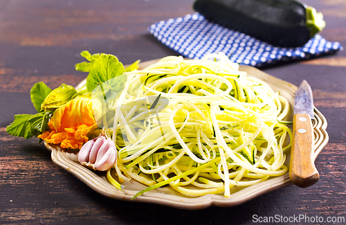 Image of Raw zucchini noodles on plate. Zucchini spaghetti in metal bowl.