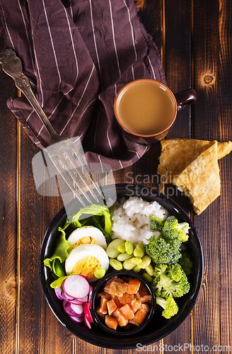 Image of Rice with red fish, green beans and broccoli in a black plate. Diet.