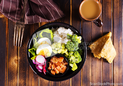 Image of Rice with red fish, green beans and broccoli in a black plate. Diet.