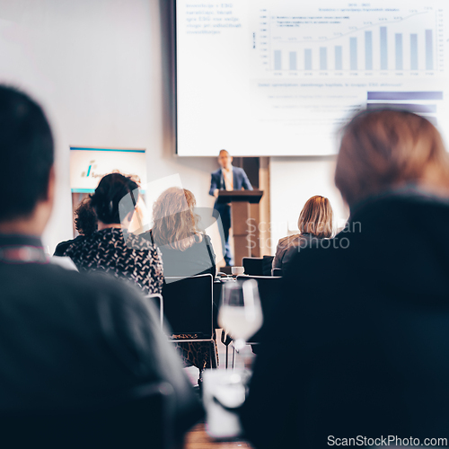 Image of Speaker giving a talk in conference hall at business event. Rear view of unrecognizable people in audience at the conference hall. Business and entrepreneurship concept.