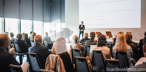 Image of Speaker giving a talk in conference hall at business event. Rear view of unrecognizable people in audience at the conference hall. Business and entrepreneurship concept.
