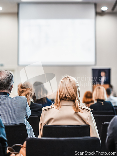 Image of Speaker giving a talk in conference hall at business event. Rear view of unrecognizable people in audience at the conference hall. Business and entrepreneurship concept.