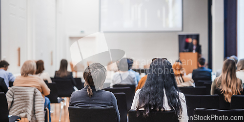 Image of Speaker giving a talk in conference hall at business event. Rear view of unrecognizable people in audience at the conference hall. Business and entrepreneurship concept.