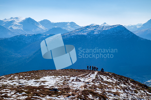 Image of Hikers explore a snowy mountain peak under clear skies during a 