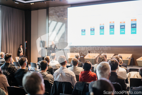 Image of Speaker giving a talk in conference hall at business event. Rear view of unrecognizable people in audience at the conference hall. Business and entrepreneurship concept.