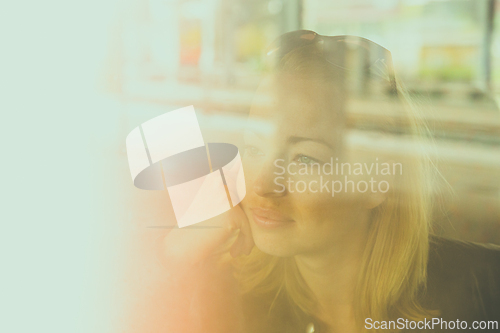 Image of Woman traveler contemplating outdoor view from window of train. Young lady on commute travel to work sitting in bus or train.