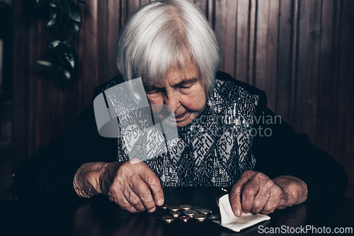 Image of Portrait of an old woman counting money. The concept of old age, poverty, austerity.