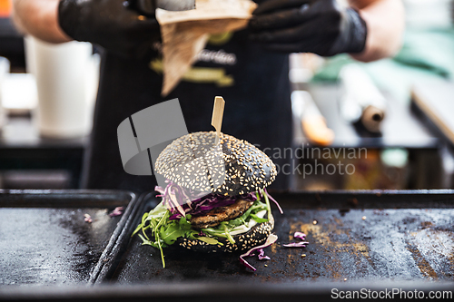 Image of Chef making healthy vegetarian salmon burgers outdoor on open kitchen, odprta kuhna, international food festival event. Street food ready to be served on a food stall.