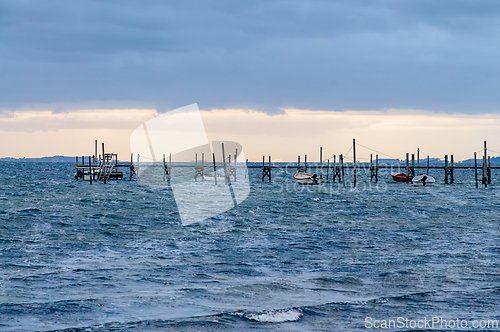 Image of Weathered pier stretches over rippling water, boats gently bobbi