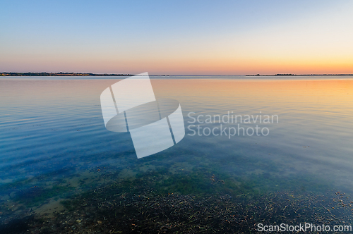 Image of Serene sunset reflection over calm water with gentle ripples and