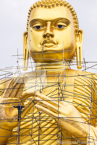 Image of Painters are painting big golden Buddha statue under construction in Thai temple