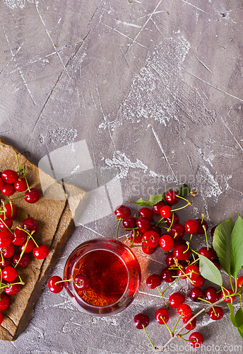 Image of Cherry juice in a transparent glass and fresh cherries